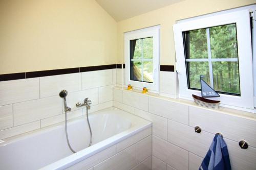 a bathroom with a bath tub and two windows at Holiday home my anchorage, Zirchow in Zirchow