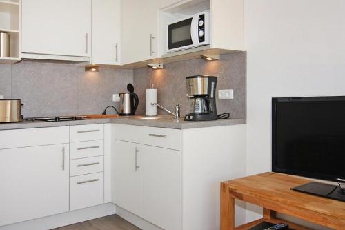 cocina con armarios blancos y TV en una mesa en Apartment, St Peter-Ording, en Sankt Peter-Ording