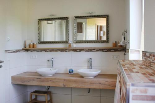 a bathroom with two sinks and two mirrors at Doppelhaushälfte Breetzer Boddentraum im Hafendorf Vieregge in Vieregge