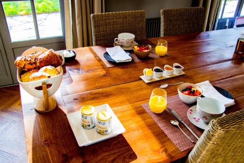 - une table en bois avec des aliments pour le petit-déjeuner et du jus d'orange dans l'établissement Les jardins de Beaumont, à Hem