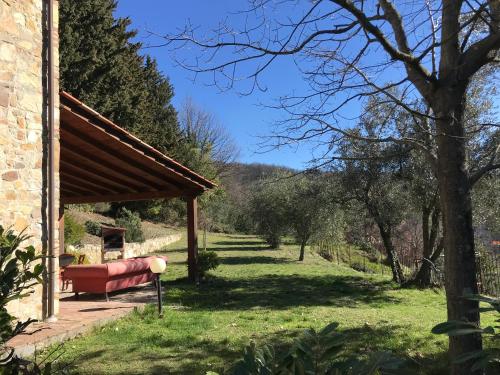 a red couch under a pavilion in a garden at Il Fiorino di Badia in Badia A Passignano