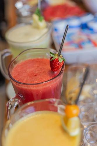 a red drink with a strawberry in a glass mug at Hotel VillaReal Charme in Guaratuba