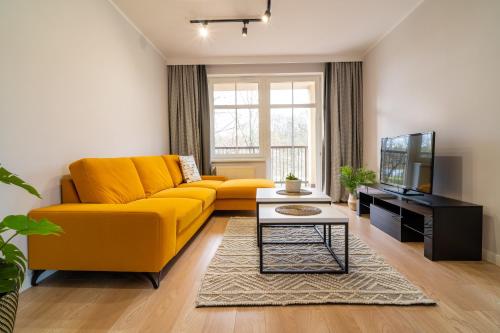 a living room with a yellow couch and a tv at Park View Apartment przy plaży in Iława