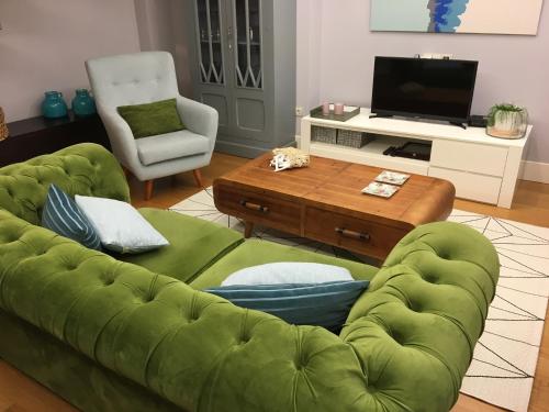 ein Wohnzimmer mit einem grünen Sofa und einem Couchtisch in der Unterkunft Bournacell 16 in Cambados