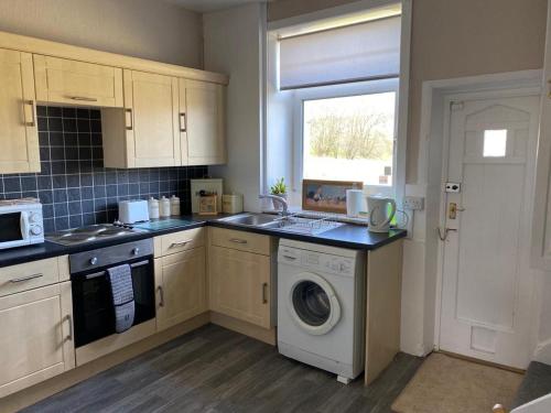 a kitchen with a washing machine and a washer at Valley Cottage in Keighley
