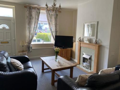 a living room with a couch and a television and a table at Valley Cottage in Keighley