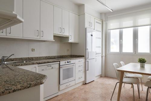 una cocina con armarios blancos y una mesa con sillas. en Always Easy I Larroca, en San Sebastián