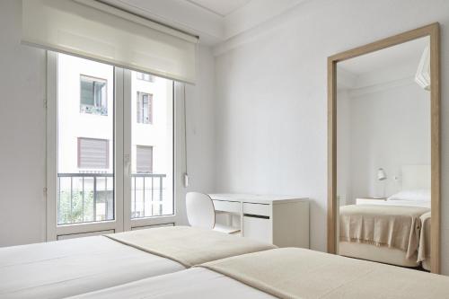1 dormitorio con espejo, cama y escritorio en Always Easy I Larroca, en San Sebastián
