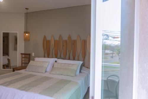 a bedroom with a bed with a wooden headboard at Hotel VillaReal Charme in Guaratuba