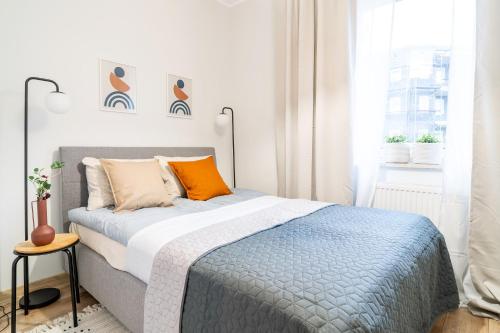 um quarto com uma cama com almofadas laranja e uma janela em Central Apartment em Iława