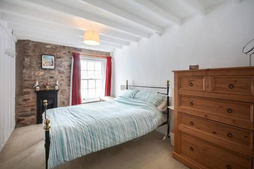 a bedroom with a bed and a dresser and a window at Rose Cottage - Kingsand in Kingsand