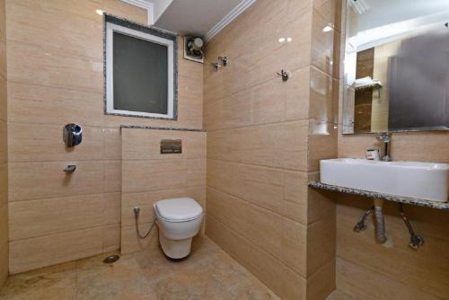 TV y baño con aseo y lavamanos. en Hotel Baba Inn-By RCG Hotels, en Nueva Delhi