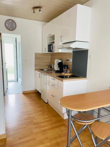 une cuisine avec des armoires blanches et une table en bois dans l'établissement Studio avec la fibre et jardin, au coeur de Lorient, à Lorient