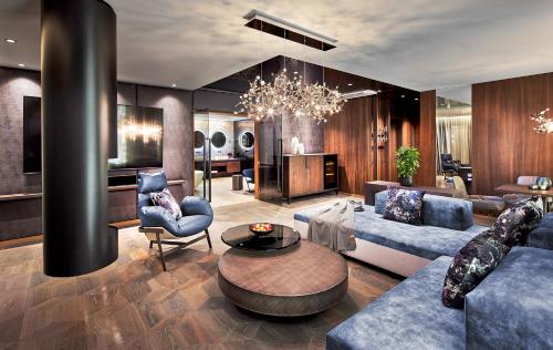 a living room with blue furniture and a chandelier at Wellness- & Sporthotel Jagdhof in Röhrnbach