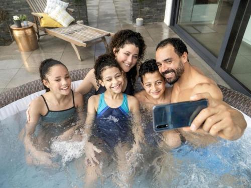 a family in a swimming pool with a cell phone at Apartamenty La Playa in Gorzewo