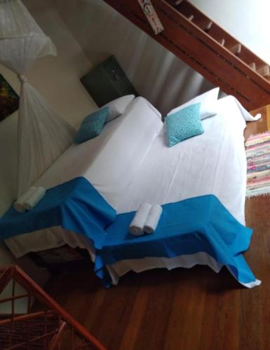 a bedroom with a bed with white sheets and blue pillows at Casa Vista al Mar in Morro de São Paulo