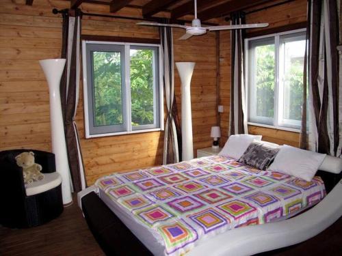 ein Schlafzimmer mit einem Bett in einem Zimmer mit Fenstern in der Unterkunft Chalet The Dream avec Piscine à 150m de la Plage in Albion