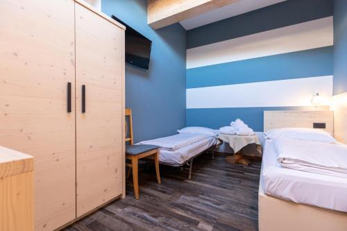 two beds in a room with blue walls at Hotel Bellavista in Cavalese