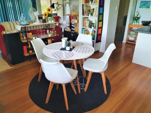 a table and four white chairs in a room at Amazing City Location-Private Room in a Share House-2 Rooms available!! in Brisbane