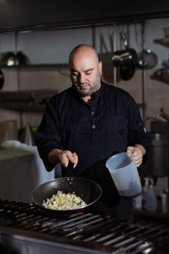 a man in a kitchen preparing food in a pan at Alianthos Garden in Plakias