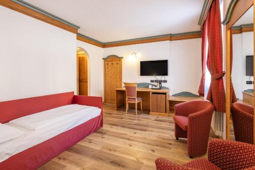 a hotel room with a bed and chairs and a desk at Hotel Bellavista in Cavalese