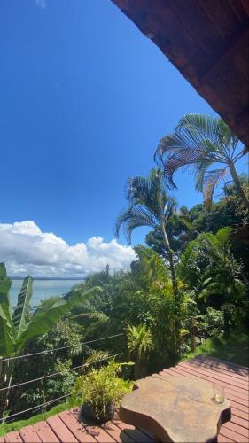 a patio with a table and palm trees and the ocean at Casa Vista al Mar in Morro de São Paulo