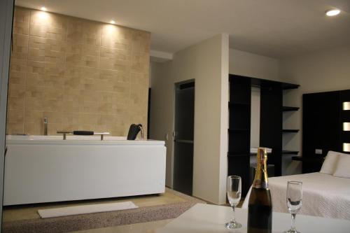 a bathtub in a bedroom with a bed and wine glasses at Hotel Marialu in Ocaña