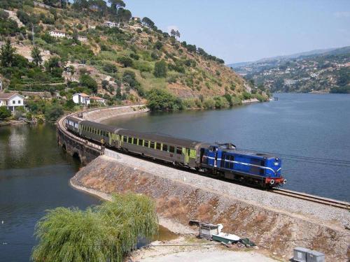 a train on a track next to a body of water at Alojamento das Caldas in Caldas de Aregos