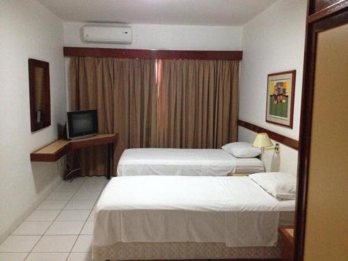 a hotel room with two beds and a television at Residence Plaza Flat in Ribeirão Preto