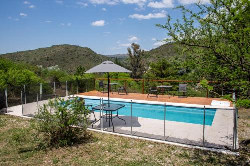 a swimming pool with a table and an umbrella at Cuesta los Robles -Casas Serranas- in Villa Icho Cruz