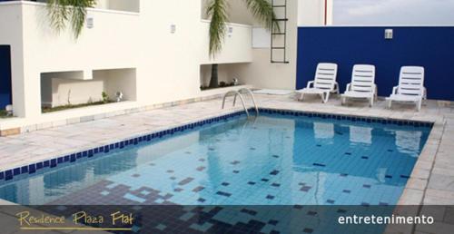 a large swimming pool with two chairs next to a building at Residence Plaza Flat in Ribeirão Preto