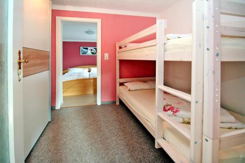 um quarto com 2 beliches com paredes cor-de-rosa em Holiday home shore view, Teupitz em Teupitz