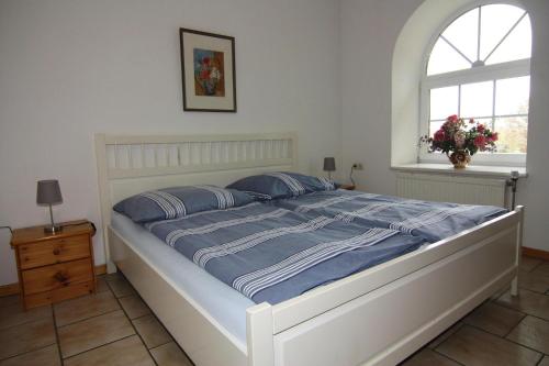 a white bed with blue sheets and a window at Ferienwohnanlage Gut Bundhorst, Stolpe in Stolpe