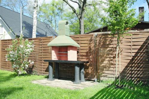 a small brick oven in a yard next to a wooden fence at Ferienhaus Storchennest 2, Falkensee in Falkensee