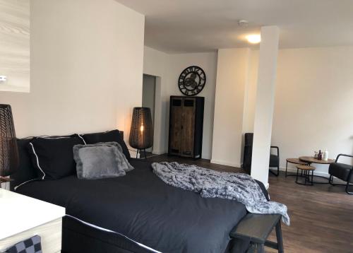 a bedroom with a black bed and a clock on the wall at BnB Grand Café Prins Bernhard in Venlo