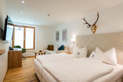 a bedroom with a large white bed and a living room at Aktiv Hotel Zur Rose am Brenner in Steinach am Brenner