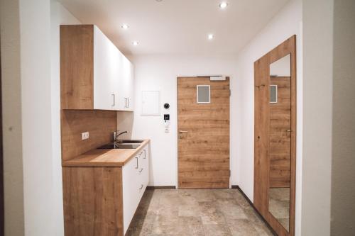 a kitchen with white cabinets and a wooden door at Aktiv Hotel Zur Rose am Brenner in Steinach am Brenner