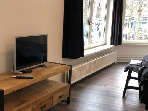 a living room with a flat screen tv on a wooden table at BnB Grand Café Prins Bernhard in Venlo
