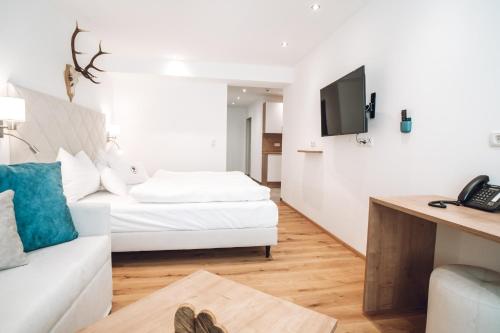 a living room with a white couch and a tv at Aktiv Hotel Zur Rose am Brenner in Steinach am Brenner