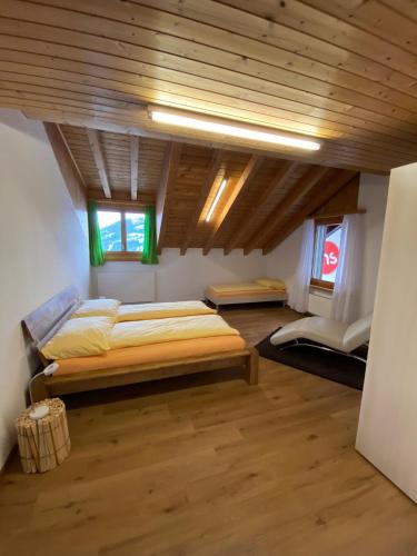 a bedroom with two beds and a wooden ceiling at Ferienwohnungen JHS in Seewis im Prättigau