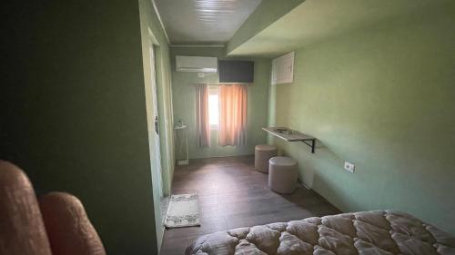 Cette chambre verte comprend un lit et une fenêtre. dans l'établissement Hotel ID, à Shkodër
