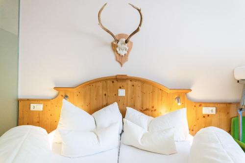 a bedroom with a bed with white pillows and a headboard at Aktiv Hotel Zur Rose am Brenner in Steinach am Brenner