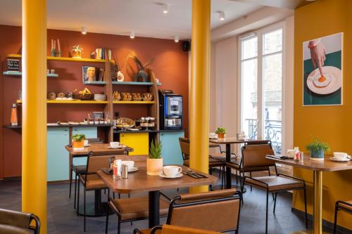 un restaurant avec piliers jaunes, tables et chaises dans l'établissement Paris Art Hotel Quartier Latin by Malone, à Paris