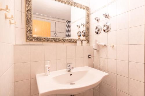 a white bathroom with a sink and a mirror at Alpendomizil 3 in Bolsterlang