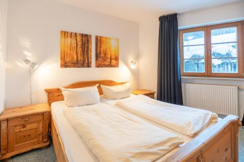 um quarto com uma cama grande e lençóis brancos em Alpendomizil 3 em Bolsterlang