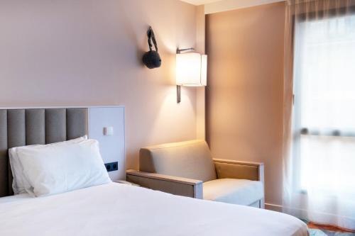 a hotel room with a bed and a chair at Mercure Amiens Cathédrale in Amiens