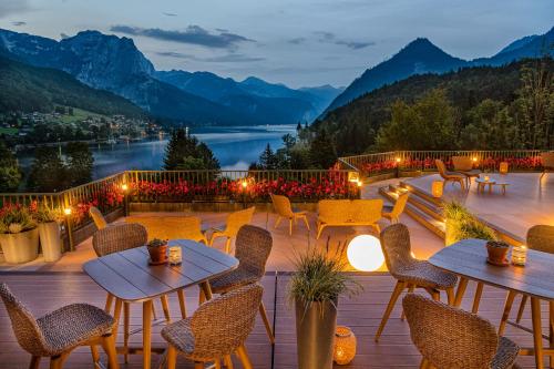 a patio with tables and chairs and a view of a lake at MONDI Appartements am Grundlsee in Grundlsee