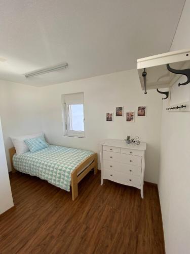 a small bedroom with a bed and a dresser at Ferienwohnungen JHS in Seewis im Prättigau