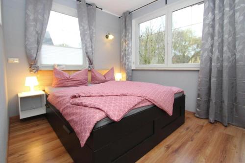 a bedroom with a bed with a pink blanket and two windows at Ferienwohnung, Malchow in Malchow