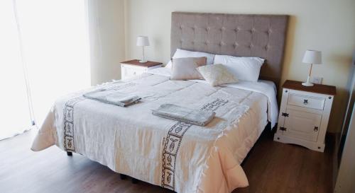 Ambar Posada Boutique في Aiguá: غرفة نوم بسرير ابيض كبير مع مواقف ليلتين